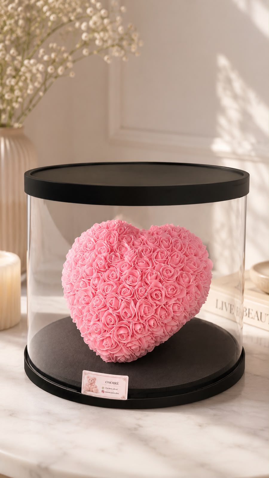 Corazón de rosas preservadas en tono rosa, bajo cúpula cilíndrica sobre base negra.